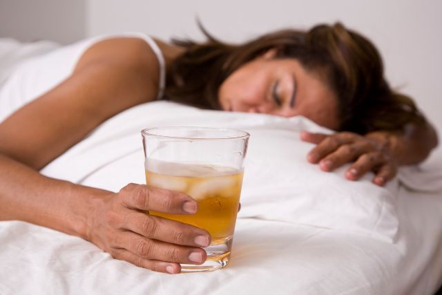 woman sleeping while holding glass of alcohol 